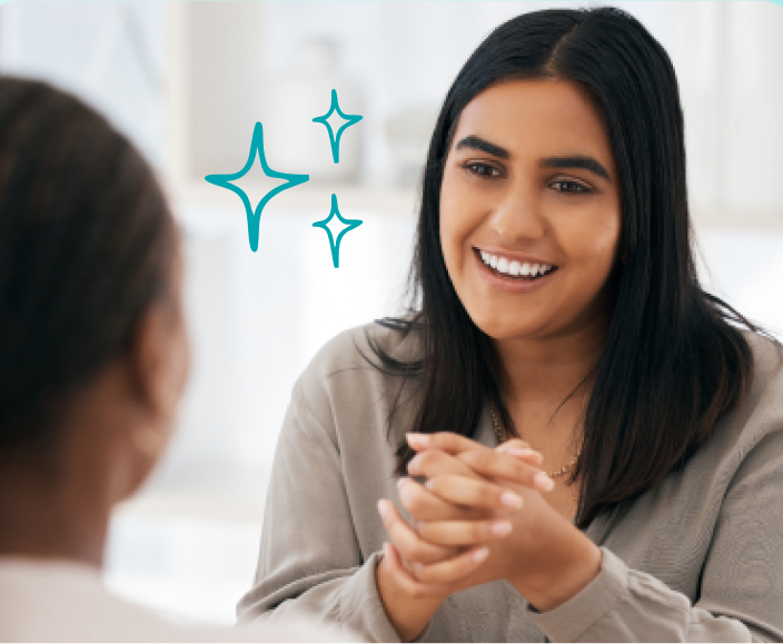 Smiling woman with long dark hair in conversation with another person, with decorative sparkle graphics nearby