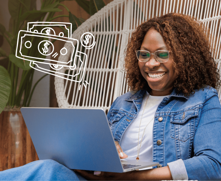 Woman smiling while using laptop with illustrated dollar bills and coin floating nearby, suggesting online financial success or earnings