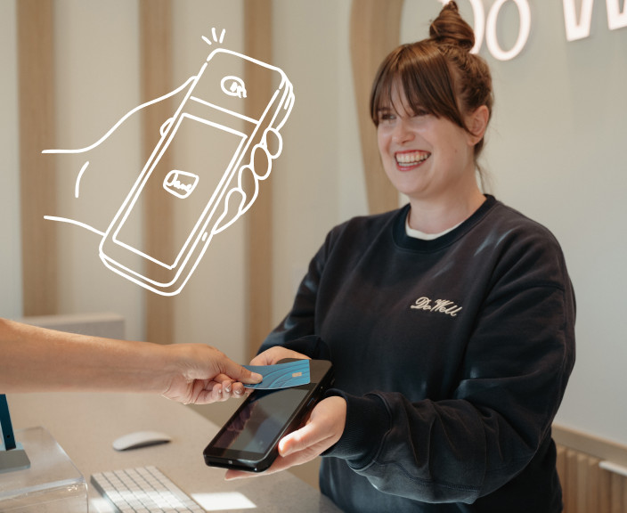 Customer making contactless payment with card at point-of-sale terminal held by smiling employee