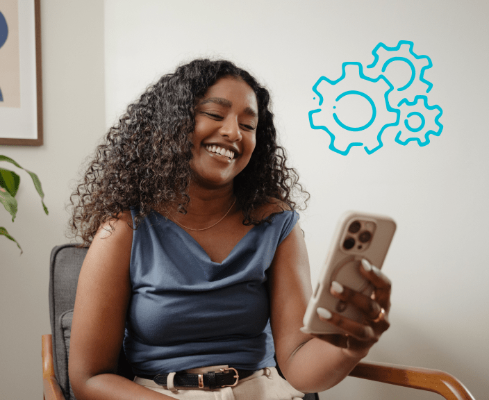 Woman smiling while looking at smartphone with blue gear icons floating nearby