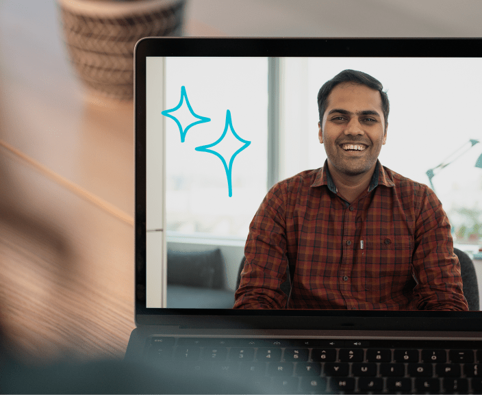 Man in plaid shirt smiling during video call on laptop screen