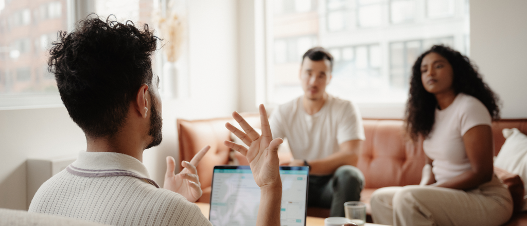 Therapist gesturing while speaking to a couple seated on a couch during a counseling session