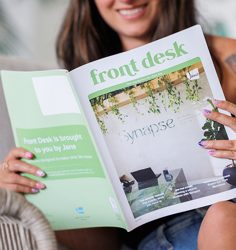 Woman reading Front Desk magazine by Jane, open to a cover story on Synapse by Park Integrative Health